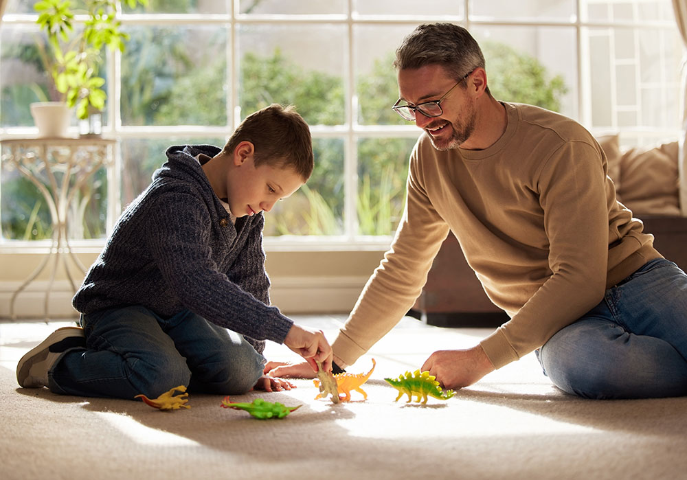 Father, kid and play with toys at house for plastic dinosaur, learning and fantasy games of animal education. Smile, family and reptiles with creative development, bonding together and childhood fun